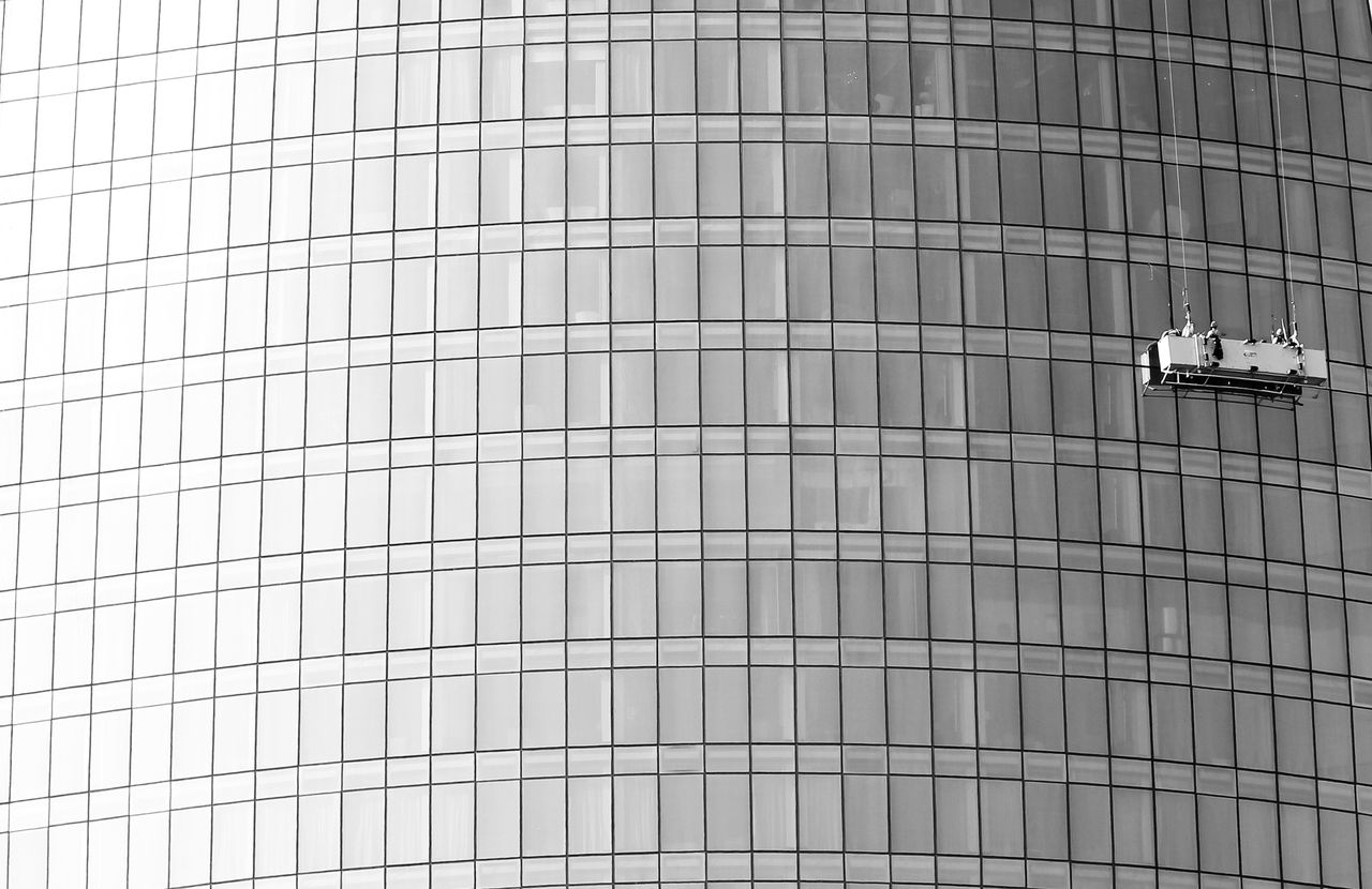 project-02-b Façade vitrée en hauteur avec une plateforme suspendue pour le nettoyage des fenêtres.