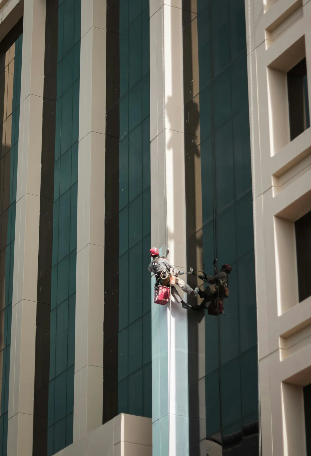 about-01 A man cleaning skyscraper windows with a harness, showcasing urban high-rise work.